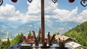 A wooden table with decorative items, a view of mountains, and a clear sky. - Room 'Camoscio' – Space and Comfort with Balcony and Alpine Views (Charvensod)