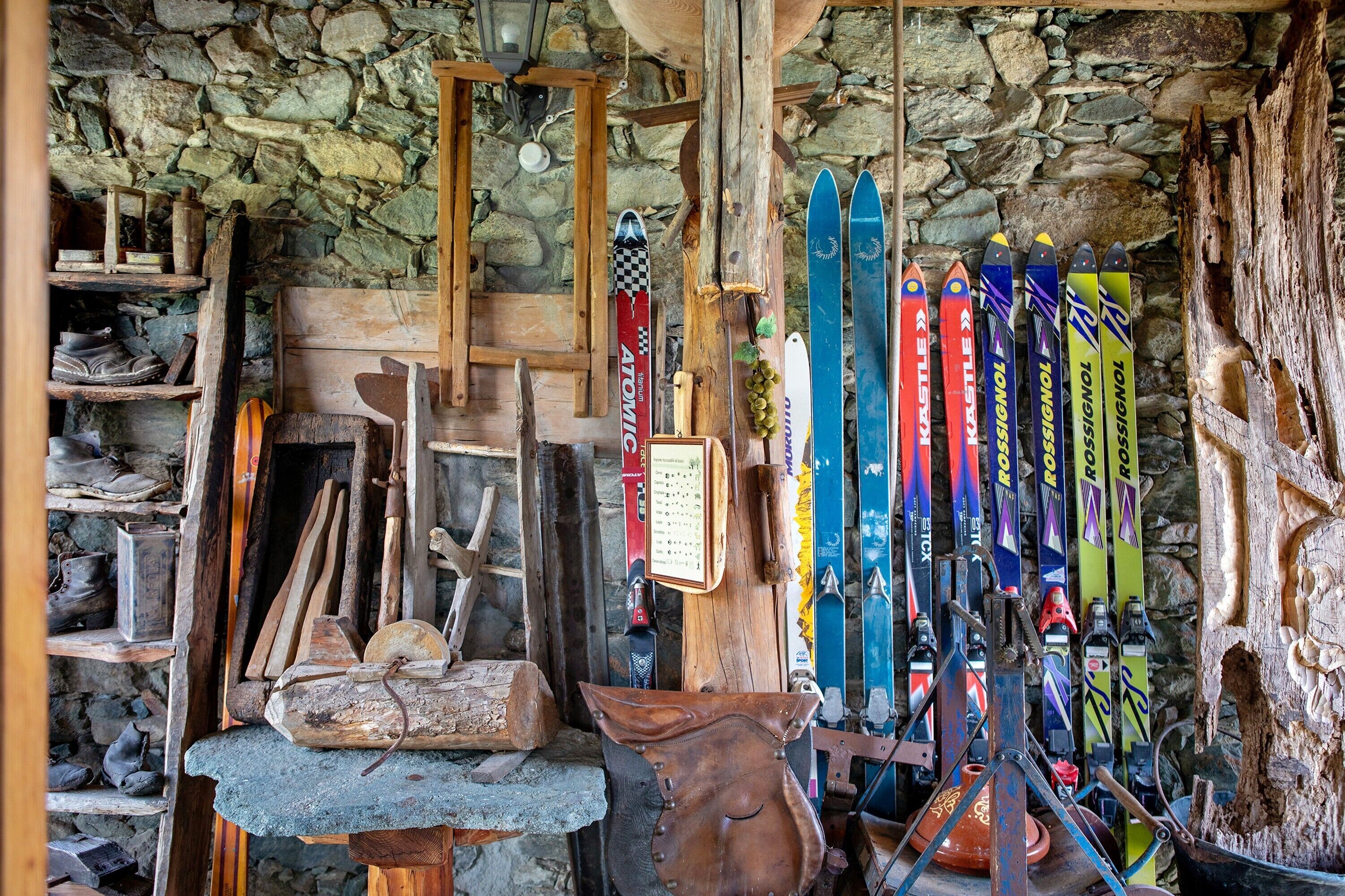 Ein rustikales Interieur mit Holzböden, Skiern und einer Steinwand.