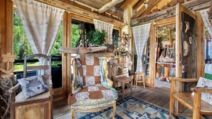 A rustic cabin interior with wooden furniture, a checkered chair, and a stone fireplace. - Capriolo Room – Intimacy and Tranquility with Mountain Views (Charvensod)