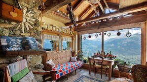 A cozy room with a stone wall, wooden furniture, a view of mountains, and a table with a basket. - Capriolo Room – Intimacy and Tranquility with Mountain Views (Charvensod)
