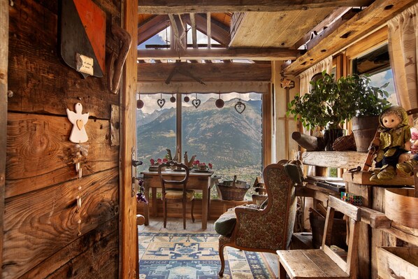 Un interior rústico de madera con vistas a la montaña, un comedor y una zona de estar acogedora.