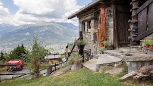 A rustic mountain cabin with stone walls, a wooden staircase, and a view of distant mountains. - Room 'Stambecco' – Mountain Atmosphere on Two Levels with Panoramic Balcony (Charvensod)