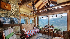 A cozy room with a stone wall, wooden furniture, a view of mountains, and a table with a basket. - Room 'Stambecco' – Mountain Atmosphere on Two Levels with Panoramic Balcony (Charvensod)