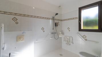 Een badkamer met witte tegels, een douche, toilet en wastafel.