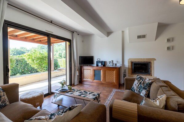 A spacious living area with a sofa, a coffee table, a television, and a fireplace.