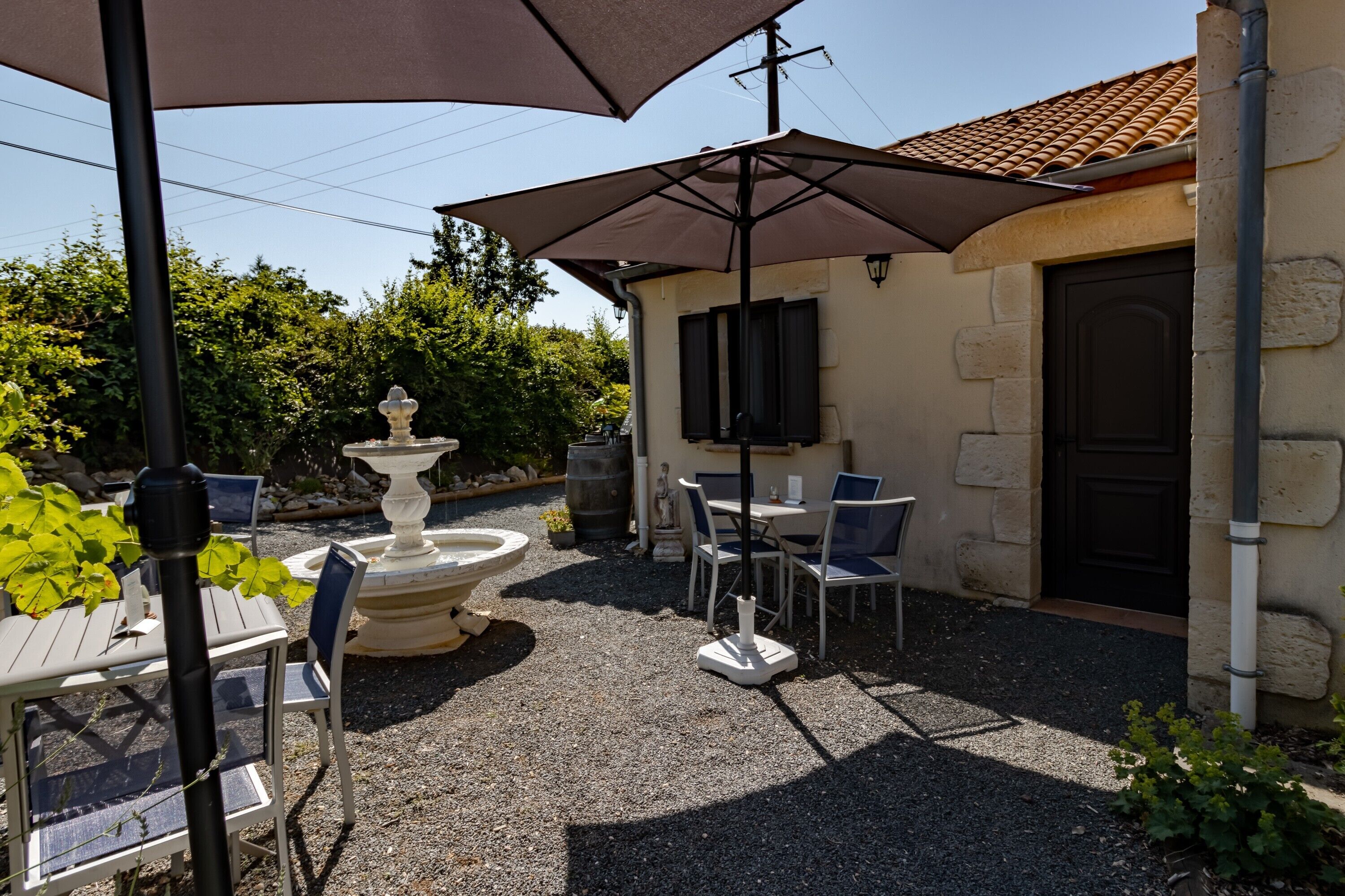 Un'area patio all'aperto con tavoli e sedie, un muro in pietra, una porta e un tetto in tegole.