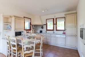 A kitchen with white cabinetry, a central island with chairs, a microwave, and a stove.