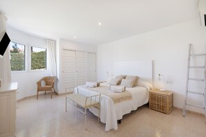 Un dormitorio con cama, mesita de noche, lámpara, silla, armario y ventana.