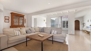 A modern living room with a sectional sofa, a wooden coffee table, and a glass cabinet. - Villa 'V206  Isabel' with Sea View, Wi-Fi and Air Conditioning (San Jaime Mediterráneo)
