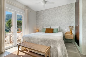 A bedroom with a bed, bench, bedside table, and a view of the outdoors. - Room 'Menta' with Mountain View, Wi-Fi and Air Conditioning (L'Atzúbia)