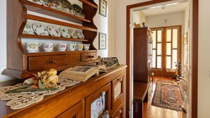 Un aparador de madera con platos decorativos, un libro, un copo de encaje y un arreglo floral.