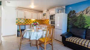 Une cuisine compacte comprenant une table à manger, des chaises, un four à micro-ondes et un réfrigérateur.