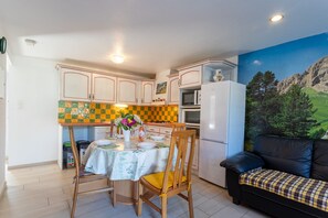 Una cocina compacta con una mesa de comedor, sillas, microondas y refrigerador.