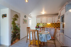 Una cocina con armarios de madera, una mesa de comedor con sillas y una planta en maceta.
