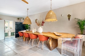 A dining area with a wooden table, orange chairs, and woven pendant lights. - Room 'Hojas' with Mountain View, Wi-Fi, and Air Conditioning (L'Atzúbia)