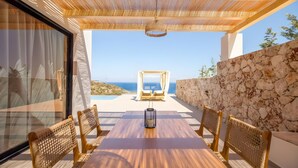 Un tavolo di legno con sedie, un lampadario e una parete in pietra.