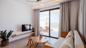 Una camera d'albergo moderna con televisione a schermo piatto, un divano, un tavolo da pranzo e vista sull'esterno.