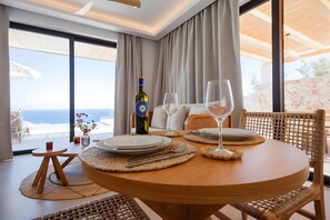 Un coin repas avec une table dressée pour deux personnes, une bouteille de vin et une vue sur la mer.