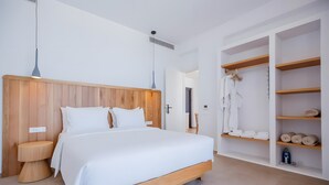 Een moderne slaapkamer met een houten hoofdbord, een groot bed, nachtlampjes en een inloopkast met planken.