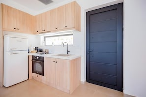 A compact kitchen with a refrigerator, oven, sink, and wooden cabinets.