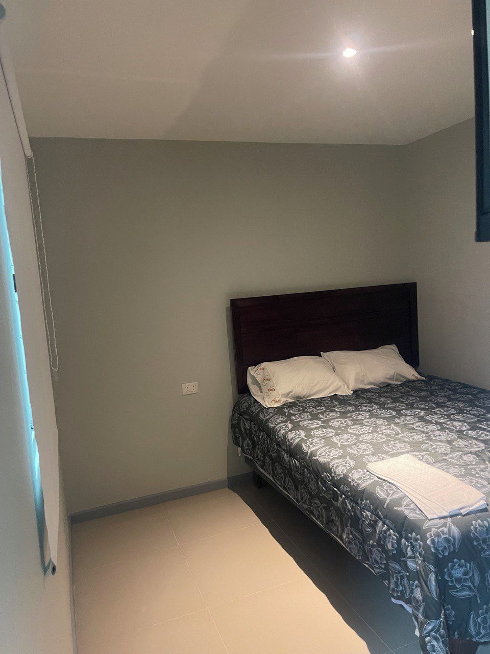 Une chambre à coucher avec un lit, une tête de lit et un luminaire au plafond.