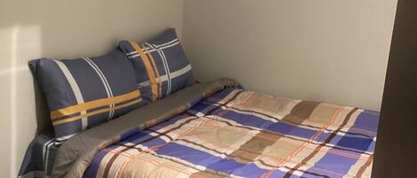 A bedroom with a bed, pillows, a bedside table, and a wall clock.
