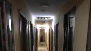 Un long couloir étroit, avec des portes de part et d’autre, menant à différentes pièces.