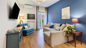Ein modernes Wohnzimmer mit blauer Akzentwand, einem Flachbildfernseher, einem Sofa, einem Couchtisch und einem Beistelltisch mit einer Pflanze.
