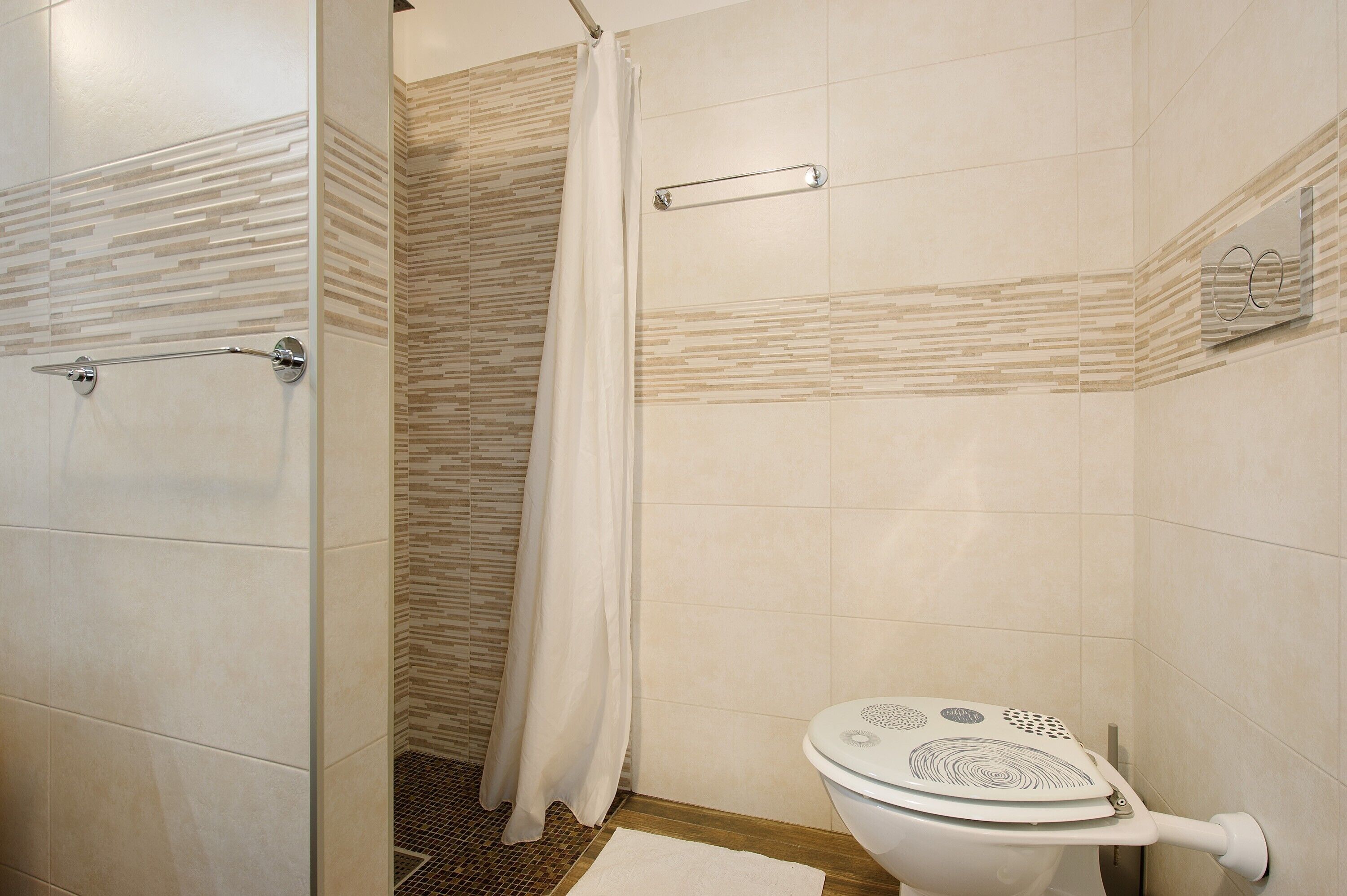 A bathroom with a shower, toilet, and a towel rack.