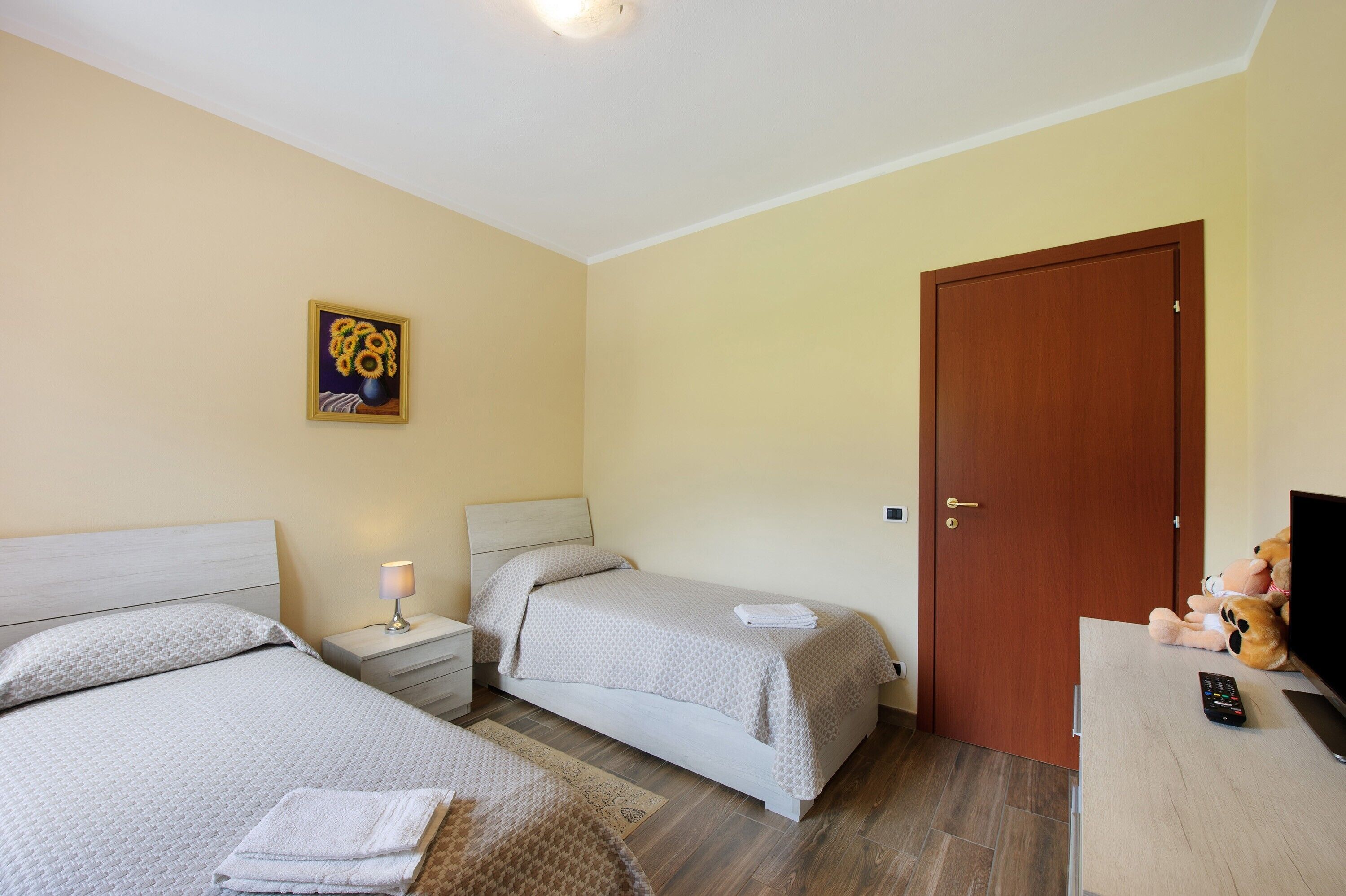Habitación de hotel con dos camas, una puerta de madera, un televisor y una lámpara.