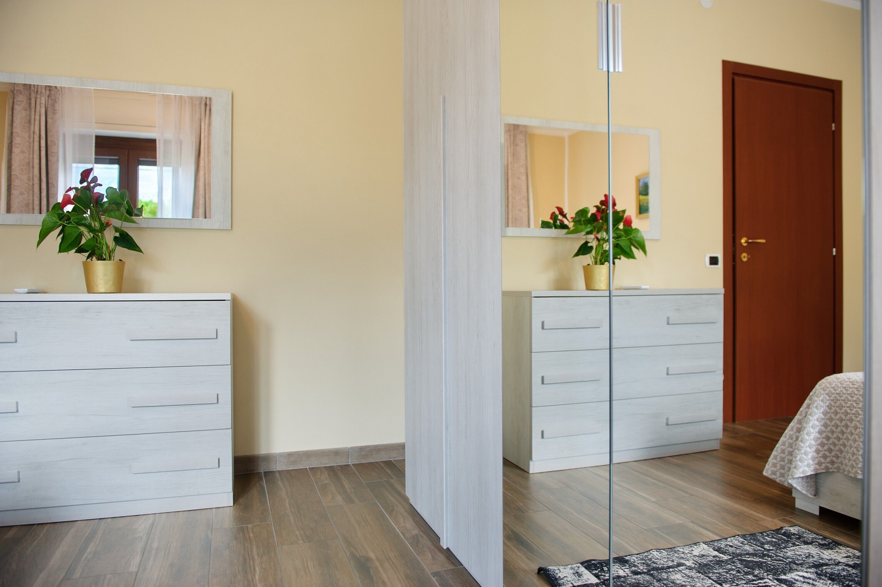 A bedroom with a bed, a dresser, a mirror, and a door.