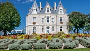 Un bâtiment historique à la façade symétrique, doté de nombreuses cheminées et d’une entrée centrale.