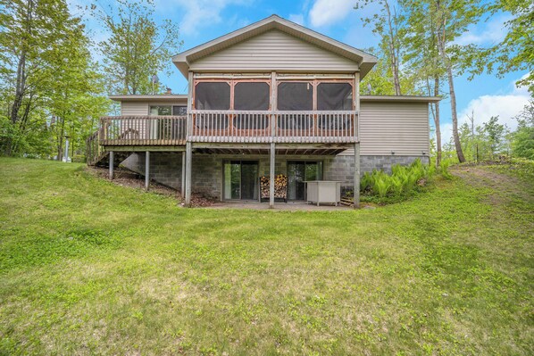 A two-story house with a balcony, a covered porch, and a fire pit area.