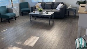A living room with a sofa, two armchairs, a coffee table, a ceiling fan, and a painting on the wall. - Newly Updated Walk to Beach & Ocean Center (Daytona Beach)