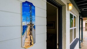 Un letrero de madera con el texto "BOARDWALK" sobre una pared blanca.