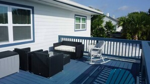 Une terrasse dotée de mobilier d’extérieur, notamment d’un canapé, de chaises et d’un fauteuil à bascule.