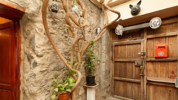 A rustic stone wall with a wooden door, a white pedestal with a potted plant, and a hanging lantern. - Holiday Home 'San Francisco 1' with Mountain View, Private Terrace and Wi-Fi (Telde)