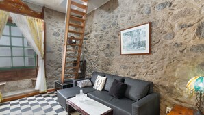 A room with a stone wall, a wooden ladder, a grey sofa, a checkered floor, and a framed picture. - Holiday Home 'San Francisco 1' with Mountain View, Private Terrace and Wi-Fi (Telde)