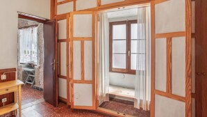 A room with a wooden partition, a window with curtains, and a small table.