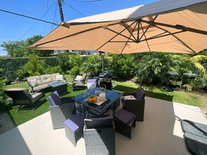 An outdoor patio with a table, chairs, and a grill. - SolunaSpa Retreat Chefs Kitchen 10 Min to Beach (Long Beach)