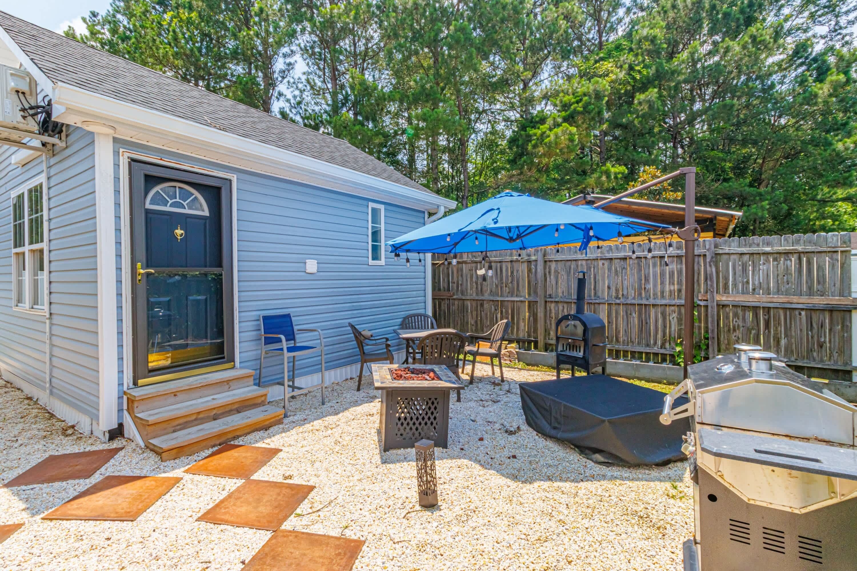 A backyard with a barbecue grill, outdoor seating, and a covered patio area.