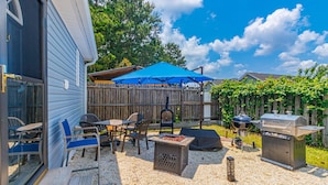 A patio with outdoor furniture, a barbecue grill, and a wooden fence. - 148 Rockdale Street Tiny House (Myrtle Beach)