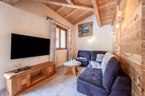 A wooden interior with a flat-screen TV, a sofa, a bench, and a small table. - Apartment 'Savine' with Mountain View, Balcony and Wi-Fi (Val-Cenis)