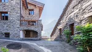 Un edificio de piedra con un balcón, una puerta de madera y vistas a la montaña.