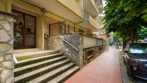A building with stone steps leading to a door, a brick-paved sidewalk, and a parked car. - Apartment 'Casa Nonna Adri' with Shared Terrace and Wi-Fi (levanto)