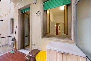 Une entrée d’immeuble avec un auvent vert, une porte et une fenêtre dont le reflet est visible.