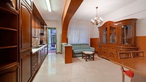 A spacious living area with a wooden cabinet, a sofa, and a dining table. - Apartment 'Casa Nonna Adri' with Shared Terrace and Wi-Fi (levanto)