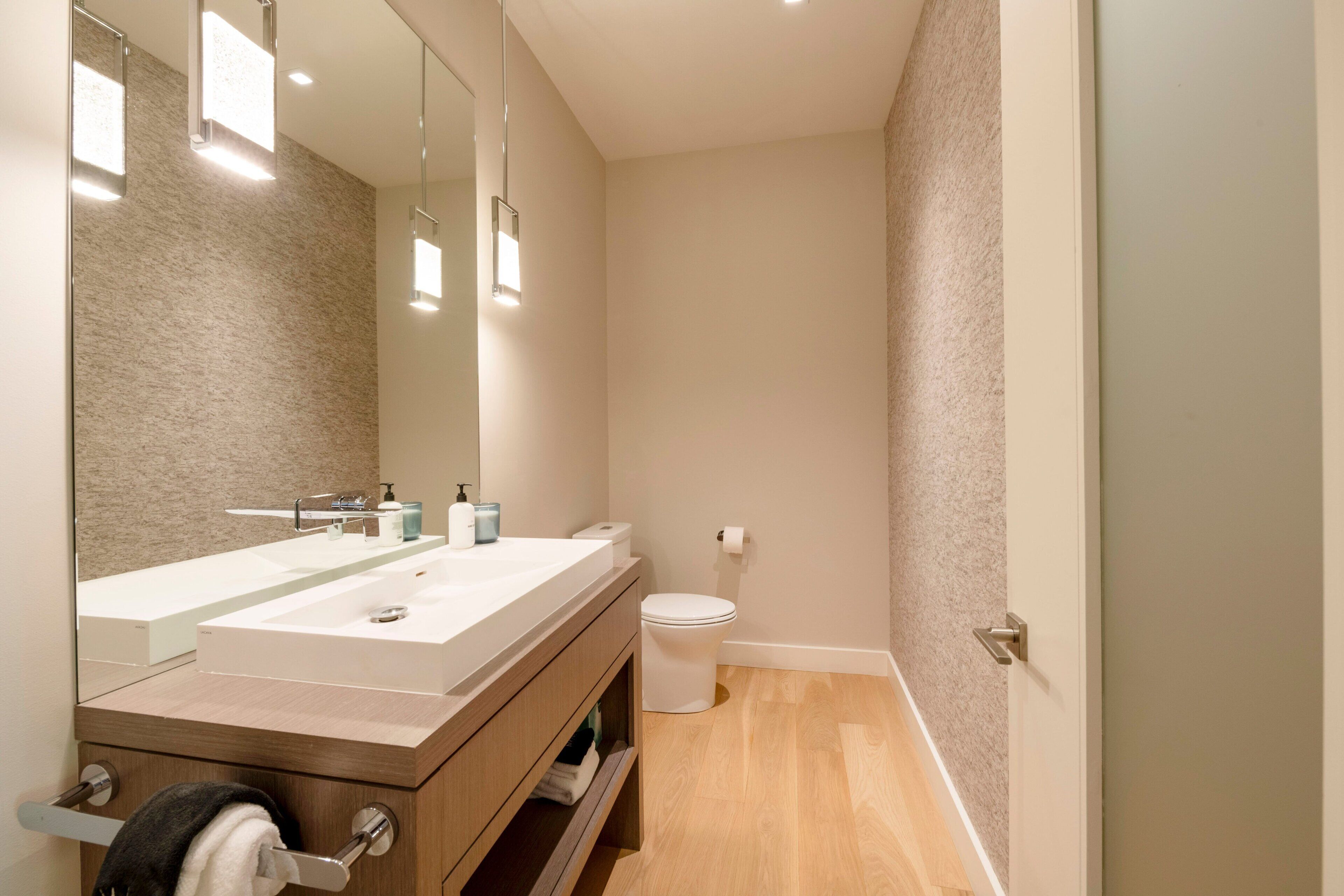 Un baño moderno con tocador de doble lavabo, inodoro y espejo.