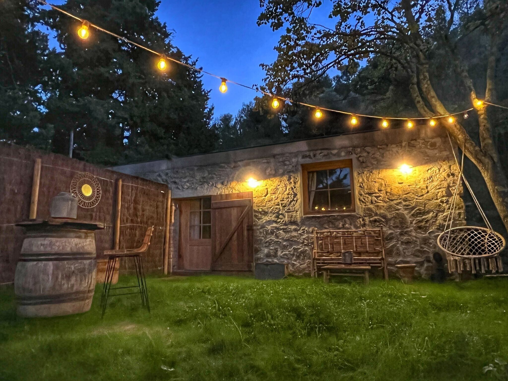Un bâtiment rustique en pierre, doté d’une porte en bois, d’une fenêtre et d’un banc.