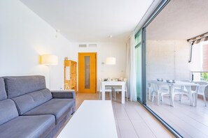 Ein modernes Wohnzimmer mit einem grauen Sofa, einem weißen Couchtisch und einem Essbereich mit weißen Stühlen und einem Tisch.
